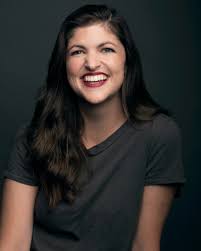 Lauren Shippen smiling in a dark t-shirt, dark background.